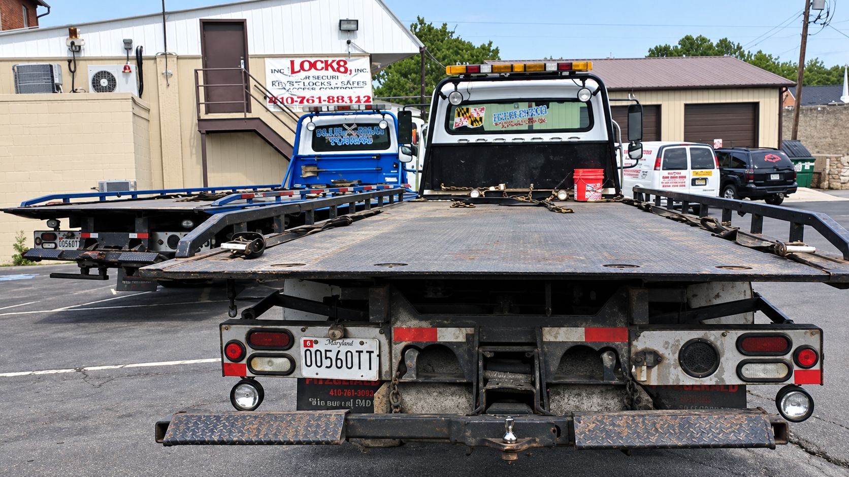 Rear view of a Blue Gray flatbed rollback carrying a car in a parking lot