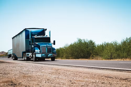 Blue semi truck pulling a box trailer on a highway